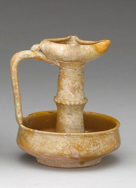 A Medieval Islamic pottery monochrome glazed oil lamp