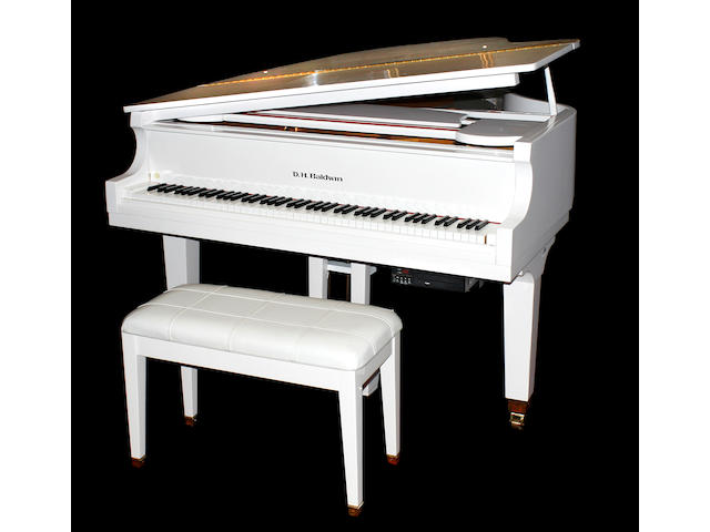 A D.H. Baldwin white lacquered grand piano and bench with an electronic disc player