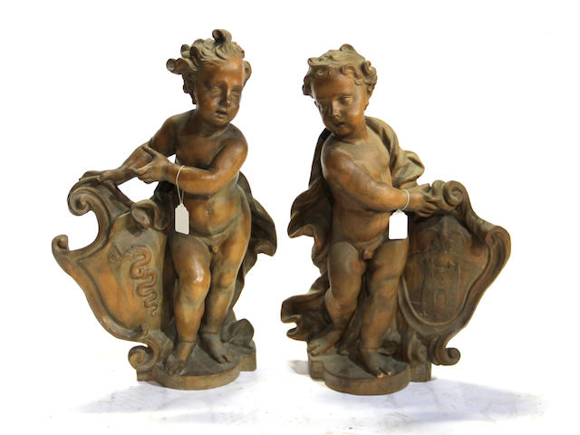 A pair of Italian glazed terracotta figures of putti late 19th/early 20th century