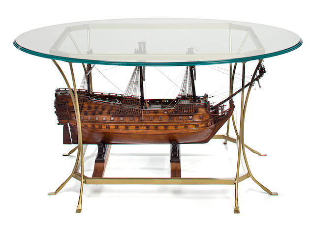 A glass side table supporting a model of an 18th century style model of a 100-gun ship-of-the-line<BR /> 20th century 44-1/2 x 32  x 21-3/4 in. (113 x 81.2 x 55.2 cm.)
