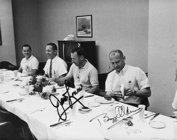 ASTRONAUTS AT LUNCH. Black and white photograph, 8 x 10 inches, with printed NASA text on verso. Framed.