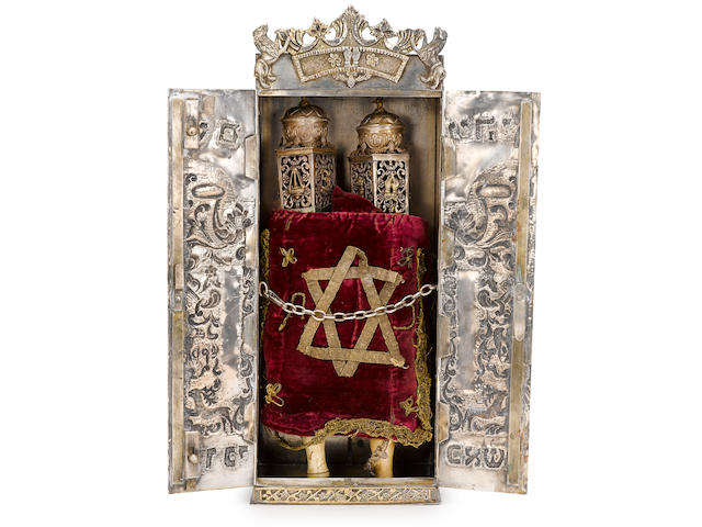 A 20th century silver Torah case with a late 19th century Italian Torah mounted on associated silver, wood, and bone rollers; in an associated silver case, 20th century, decorated in Polish style with flora and fauna.
