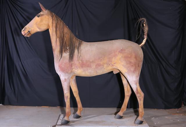 A full-size light brown plaster horse with mane,