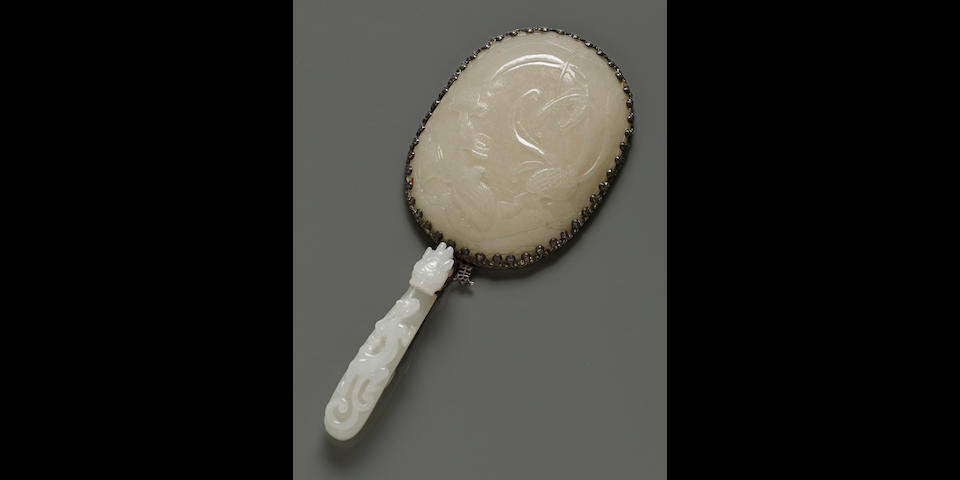 A silver hand mirror with white jade mounts