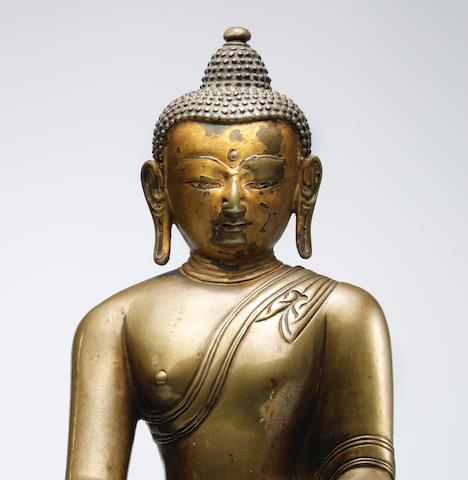 A SILVER AND COPPER INLAID BRASS ALLOY FIGURE OF SHAKYAMUNI BUDDHA TIBET, CIRCA 13TH CENTURY
