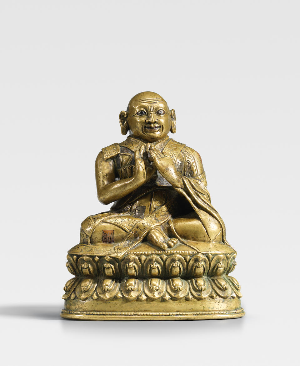 A SILVER AND COPPER INLAID BRASS ALLOY FIGURE OF A LAMA TIBET, CIRCA 15TH CENTURY