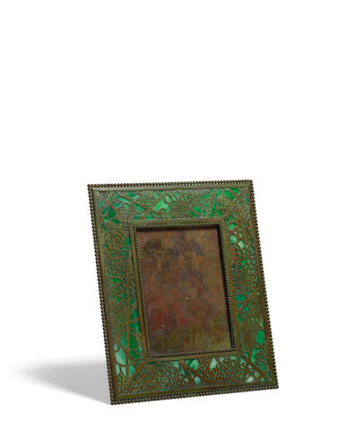 Tiffany Studios (1899-1919) Picture Framecirca 1910patinated bronze, Favrile glass, stapmed 'Tiffany Studios New York 947'height 9in (22.8cm); width 8in (20.32cm); depth 4in (10.16.cm)