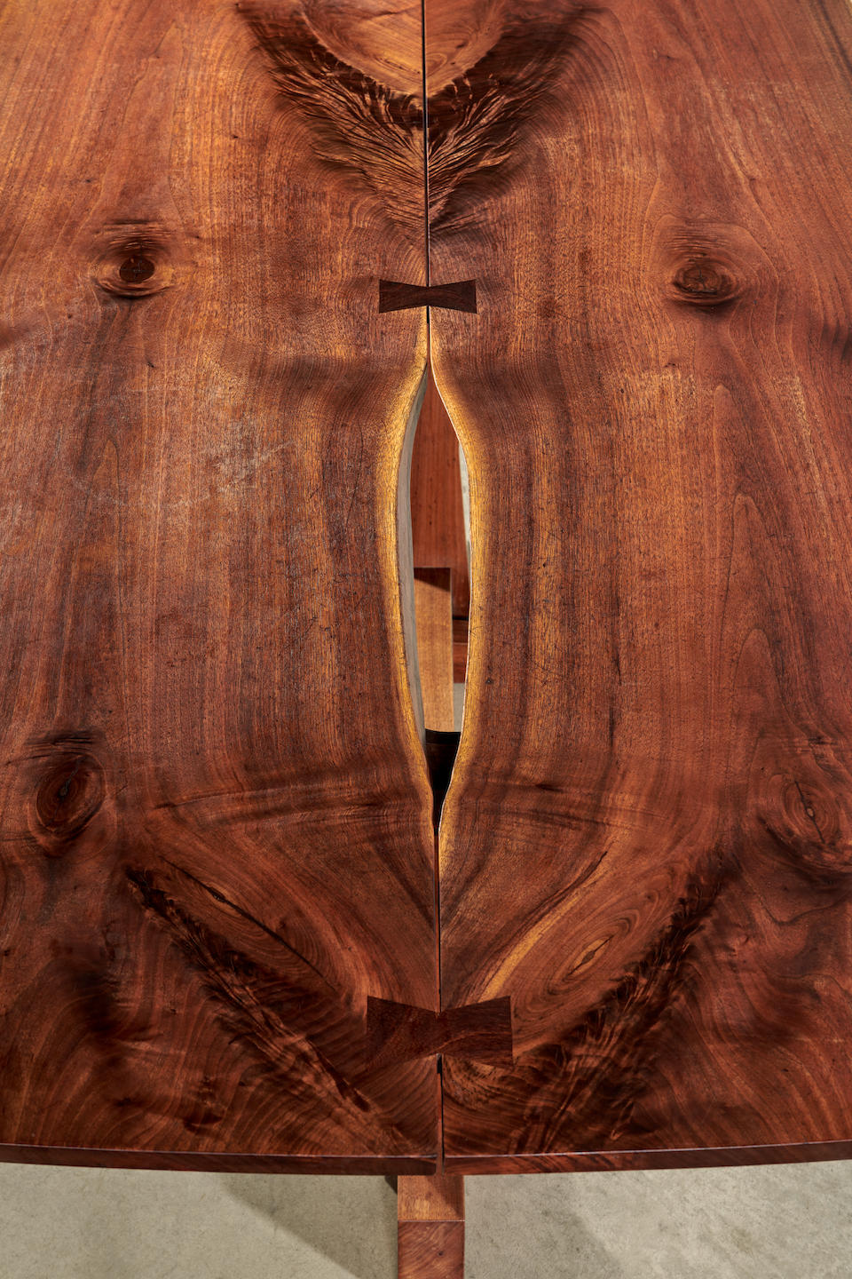 George Nakashima (1905-1990) Conoid Dining Table1976-77American black walnut, with three rosewood butterflies, two free edges and one fissure with sap-grain detail, black ink mark 'Bell'height 28 3/4in (73cm); width 72in (183cm); depth 41 1/4in (105cm)
