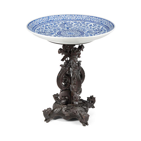 A CHINESE BLUE AND WHITE PORCELAIN CHARGER ON A FITTED CARVED HARDWOOD STAND