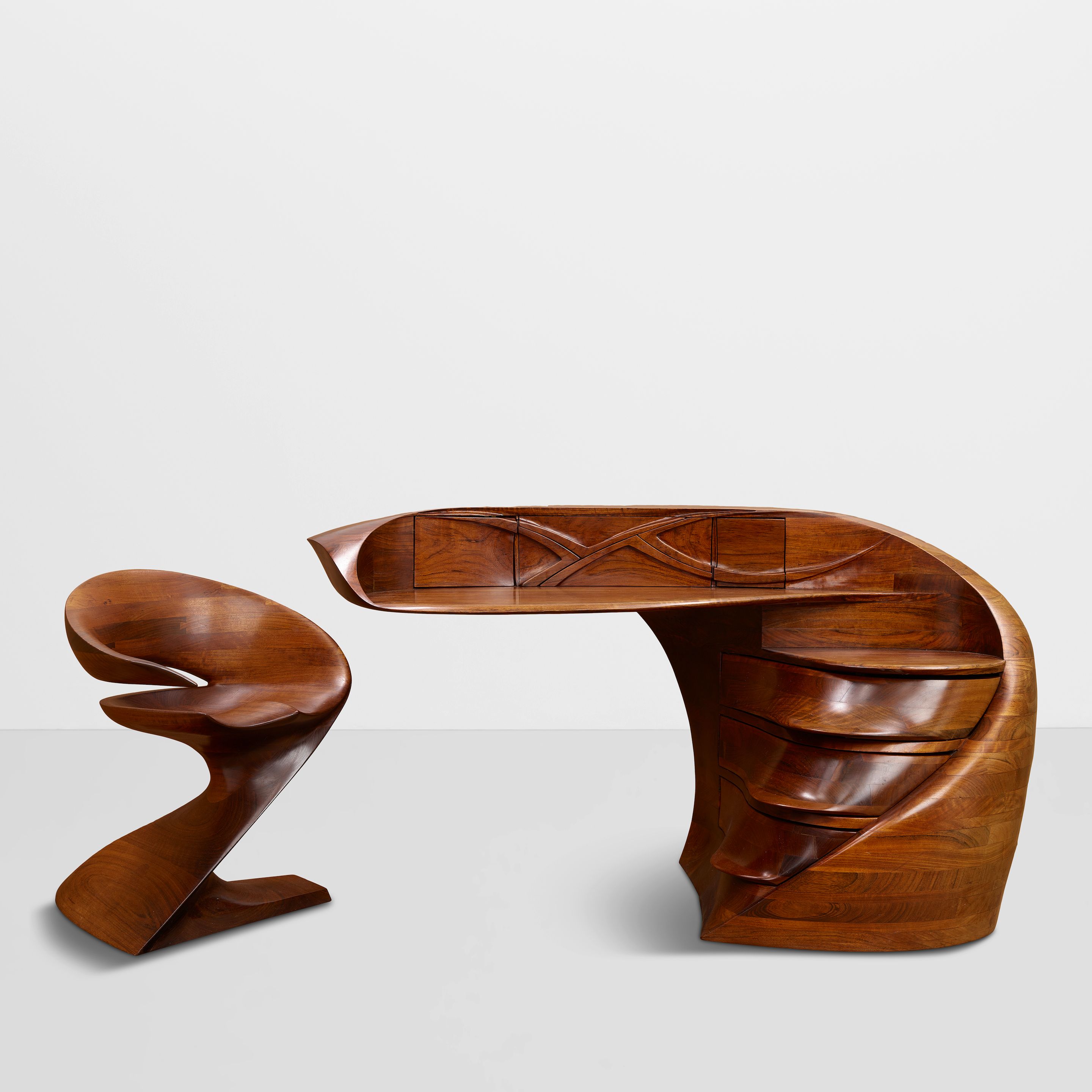MICHAEL COFFEY (1928-2024) Unique 'EL Morro' Desk and 'Matador I' Chair 1974 and 1977 Mozambique wood, desk incised 'M. Coffey 4-74', chair incised 'M. Coffey' height of desk 37in (94cm); width 72 1/2in (184.2cm); depth 31 1/2in (80cm); height of chair 30 1/4in (76.8cm); width 26 1/4in (66.6cm); depth 27 1/4in (69.3cm)
